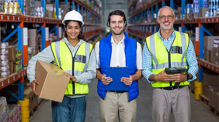 Three employees in a warehouse smiling